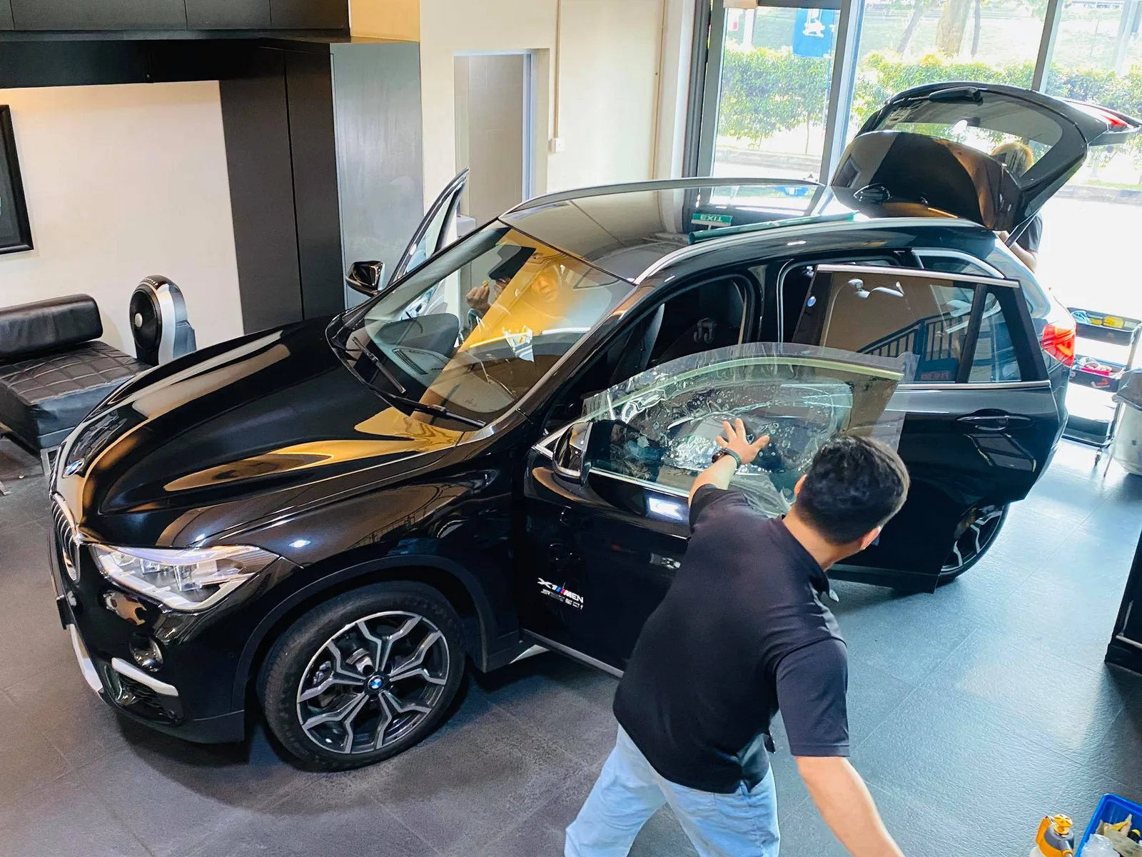 Technician applying tint film to a black BMW SUV rear door at Infratint Singapore