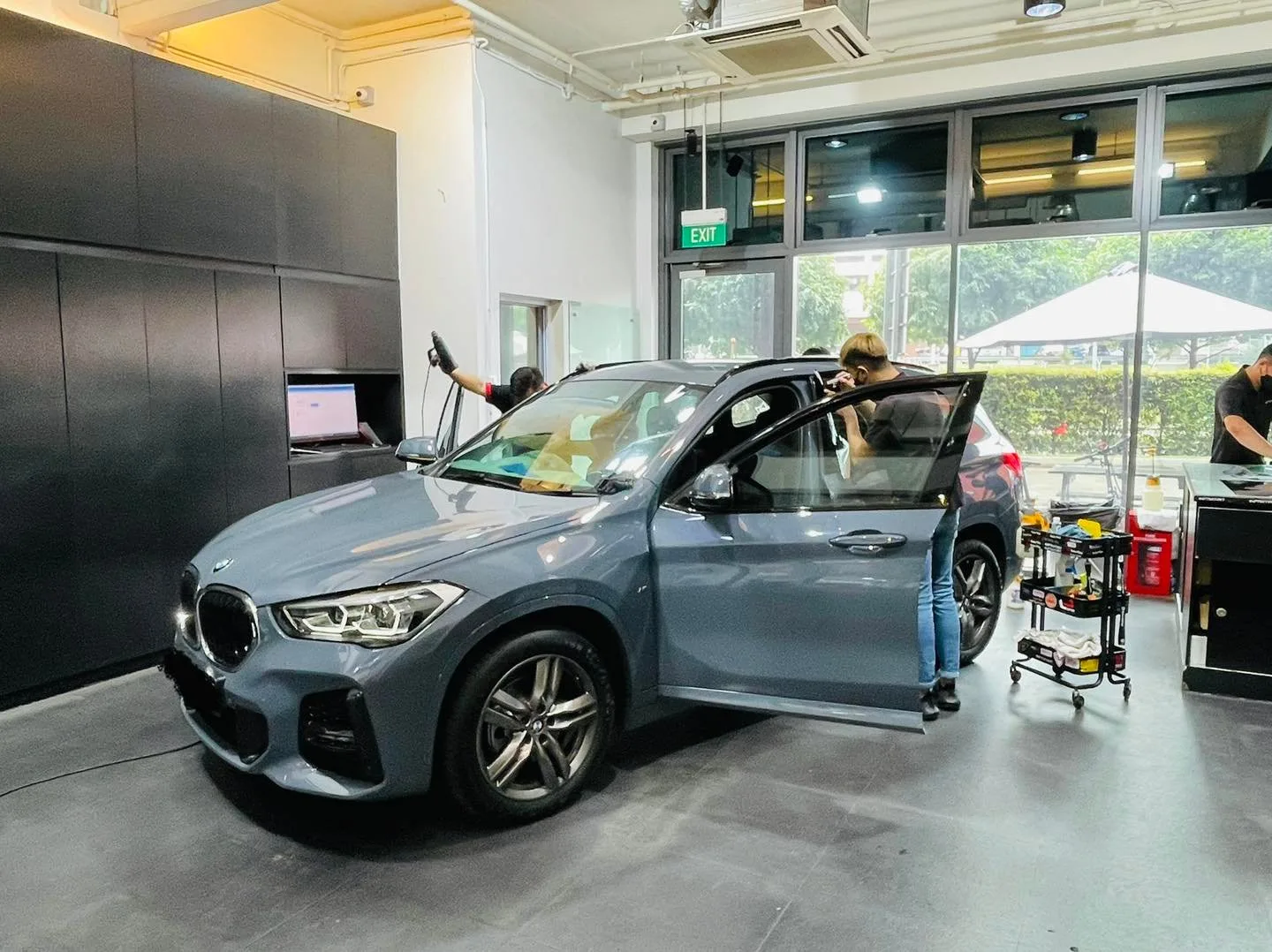 Blue-grey BMW X1 SUV with doors open during solar film install at Infratint Singapore