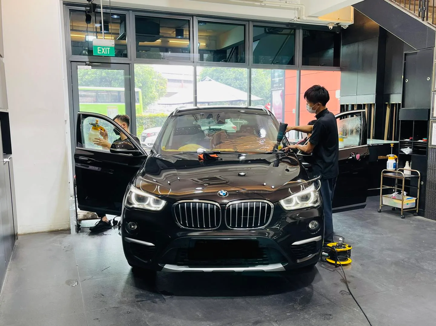 Technician tinting a dark BMW X1 windscreen at Infratint Singapore
