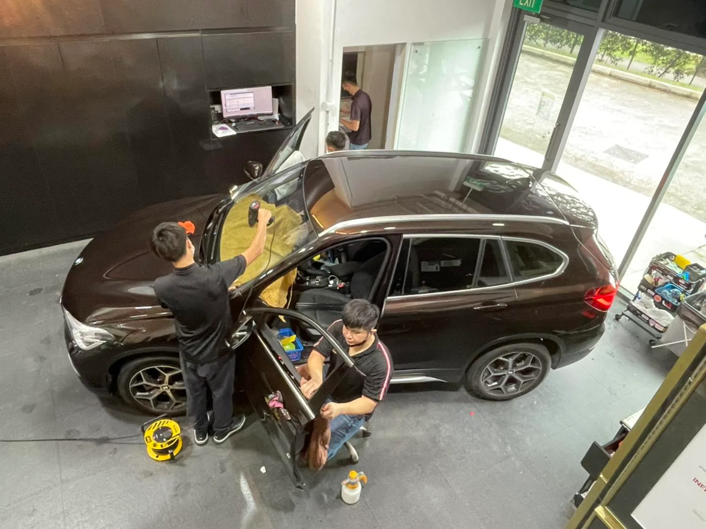 Overhead view of technicians tinting a brown BMW X1 at Infratint Singapore