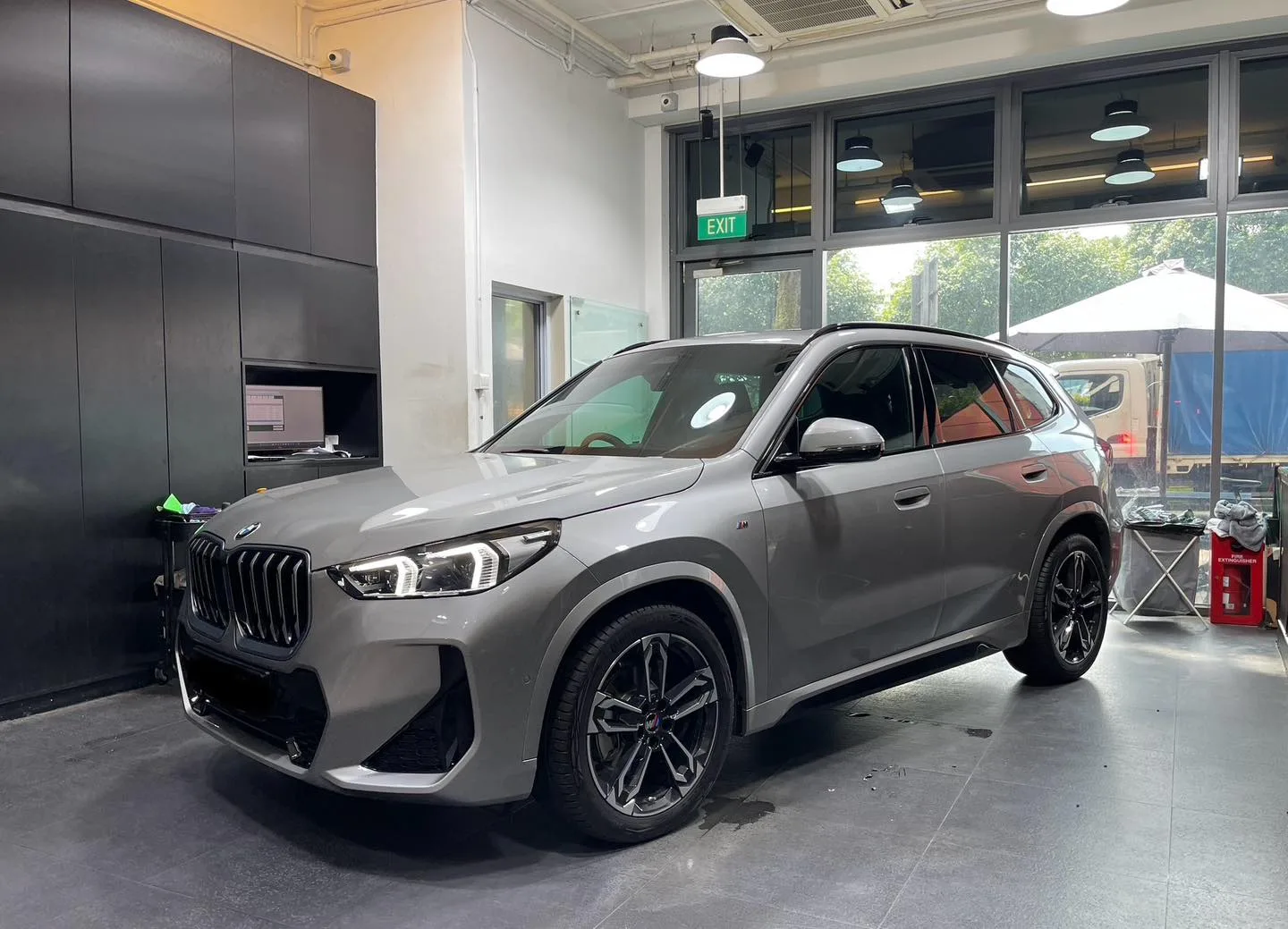 Silver BMW X1 front three-quarter inside the Infratint workshop bay
