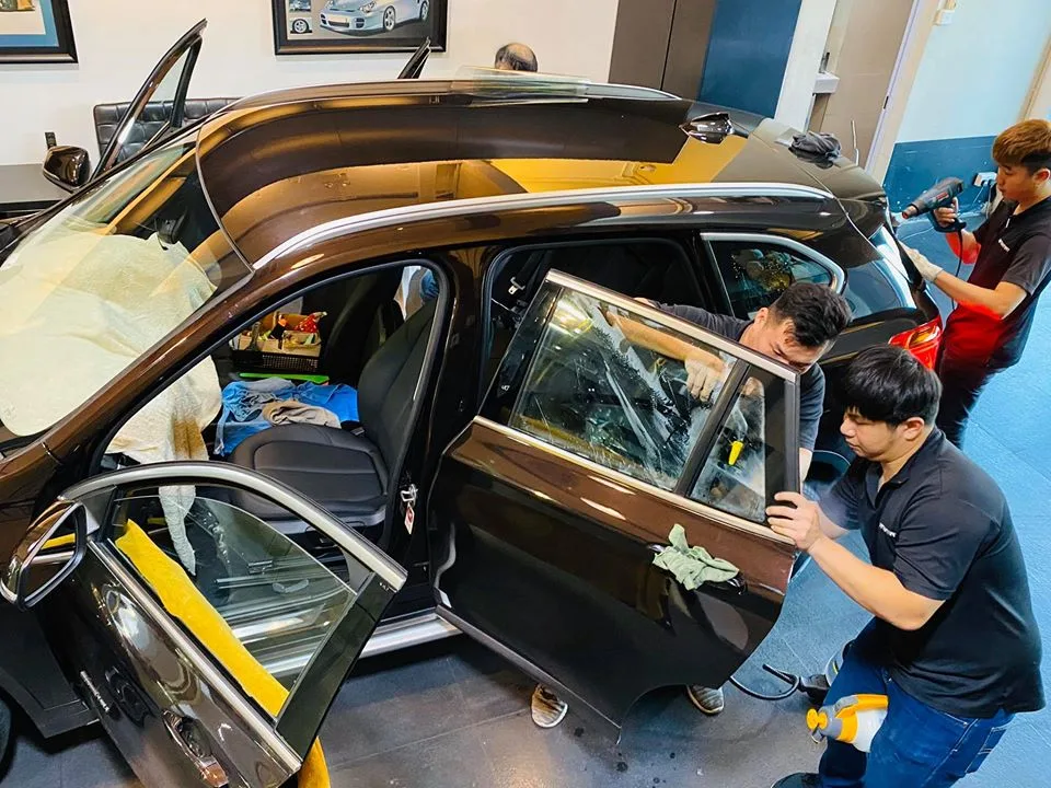 Technicians fitting window film to a BMW X1 rear door at Infratint Singapore