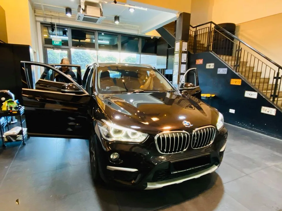 Dark BMW X1 with doors open for window tinting at Infratint Singapore
