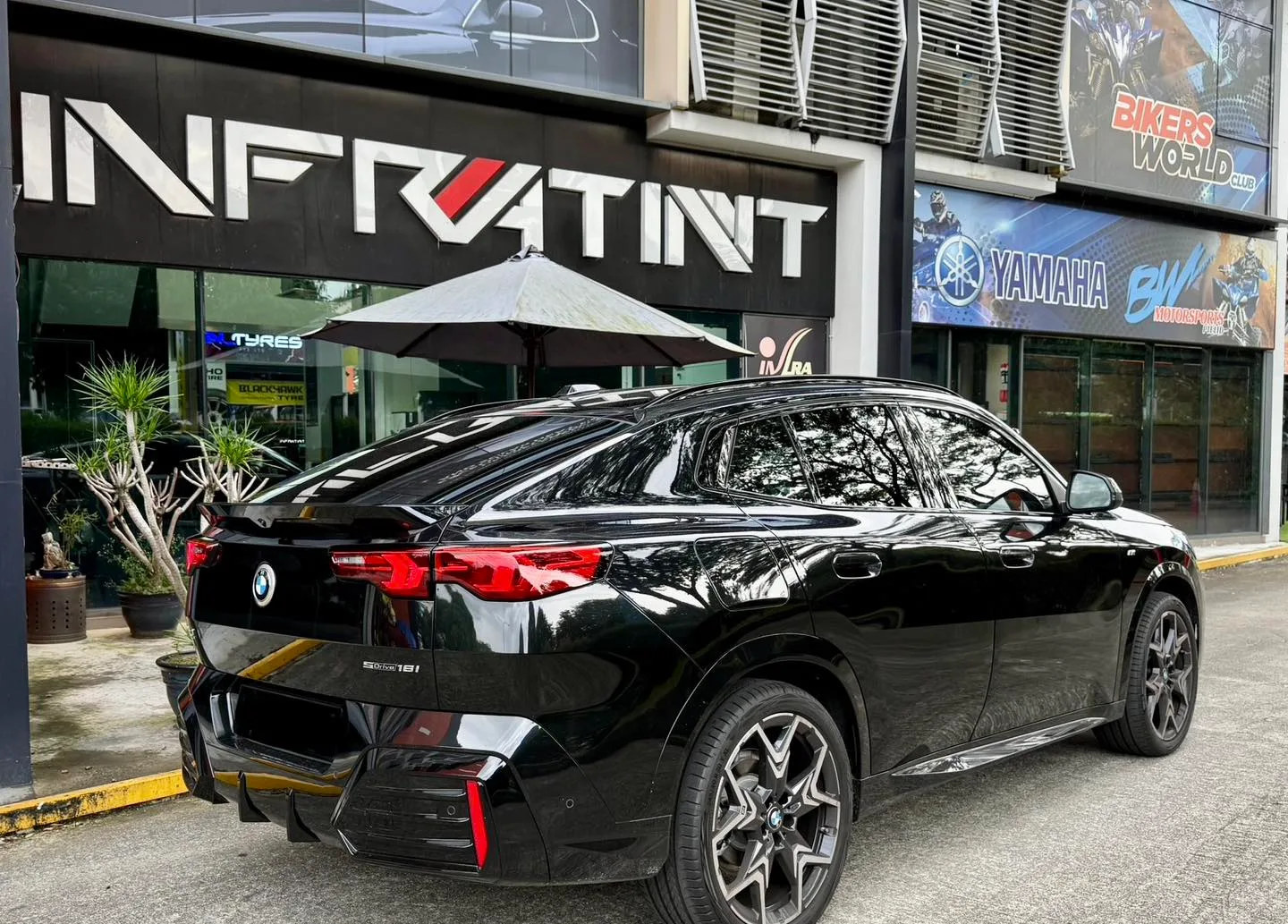 Tinted black BMW X2 rear three-quarter view outside the Infratint shopfront in Singapore