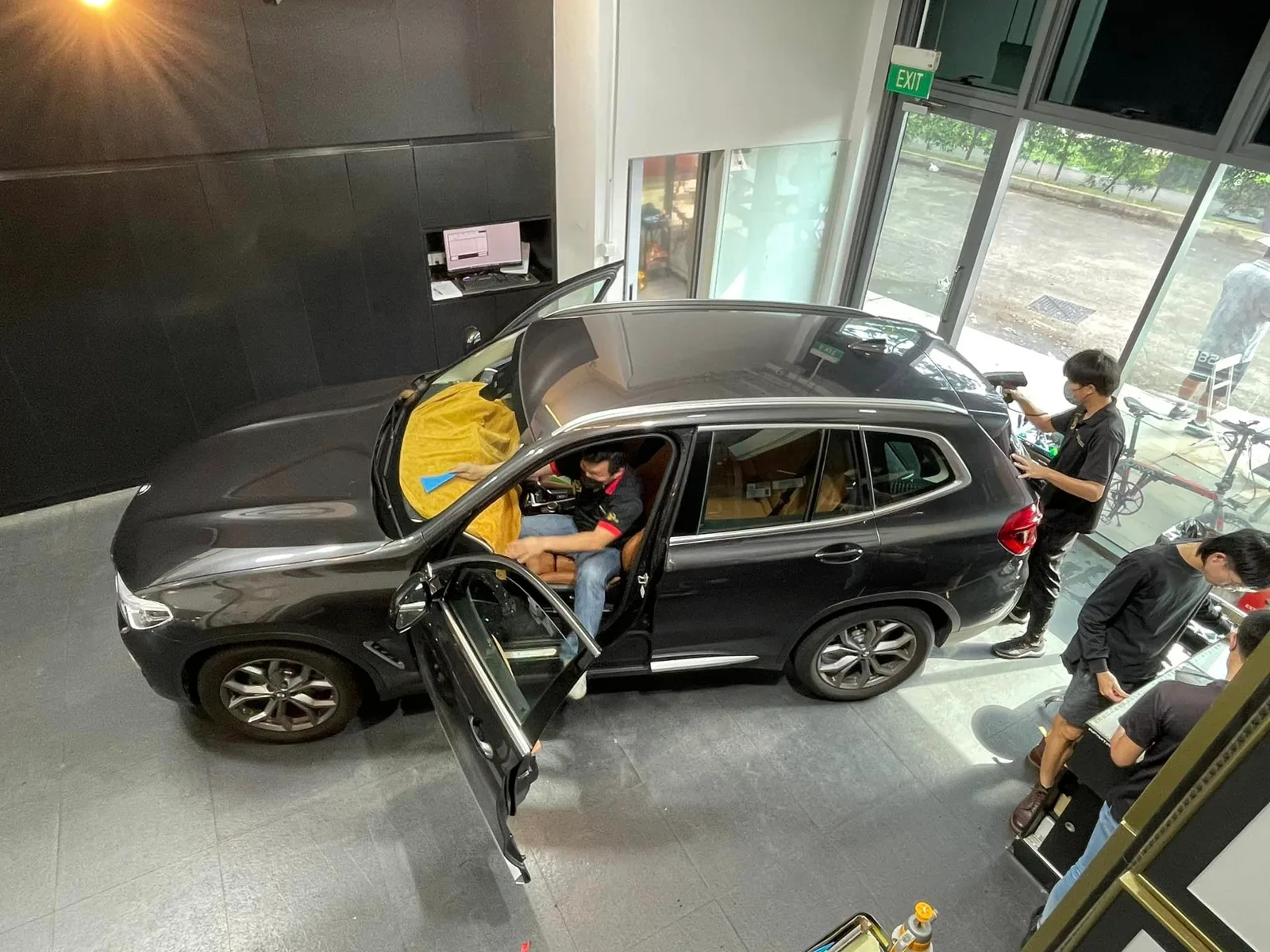 Overhead view of installers tinting a dark BMW X3 at Infratint Singapore