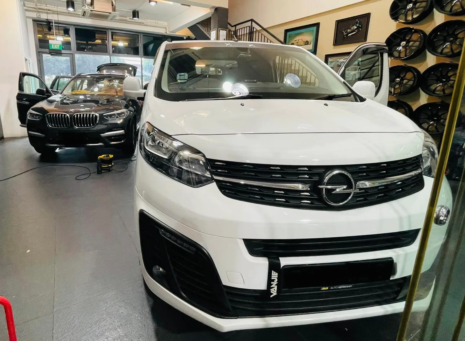 White Opel Vivaro van and grey BMW X3 inside the Infratint Singapore showroom for window tinting