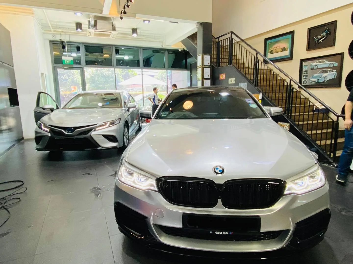 Silver BMW 5 Series and silver Toyota Camry inside the Infratint Singapore showroom