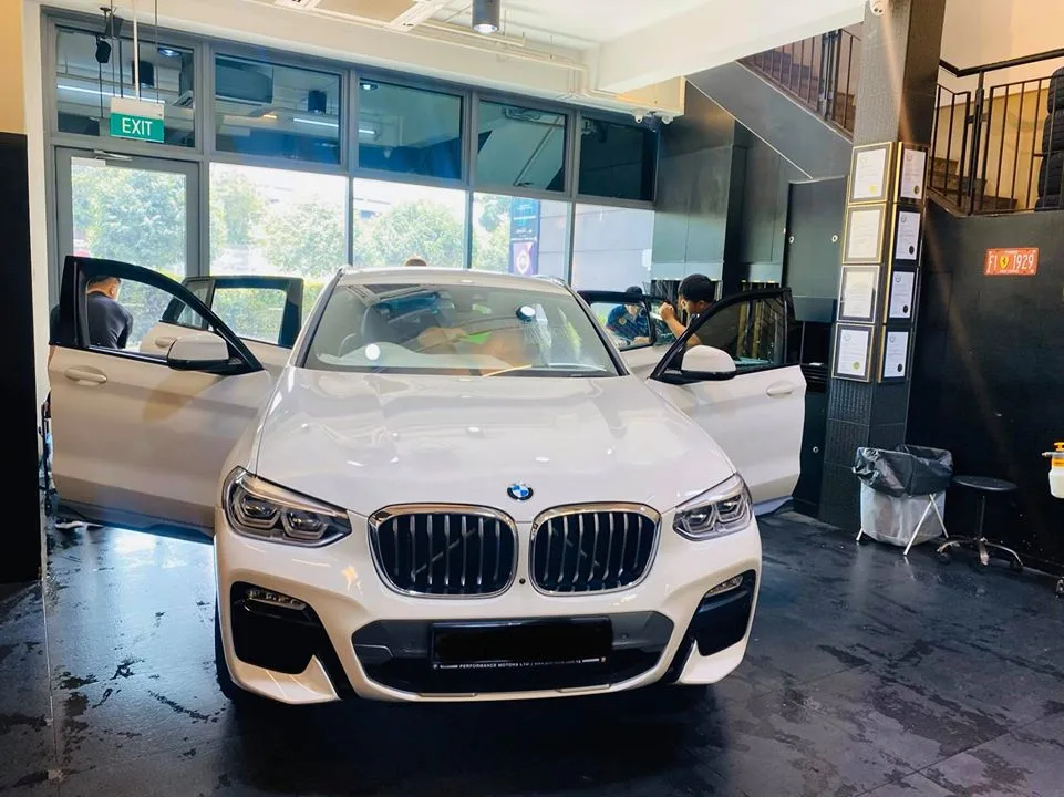 White BMW X4 with doors open during window tinting at Infratint Singapore