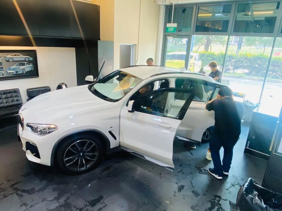 Technician applying window film to a white BMW X4 at Infratint Singapore