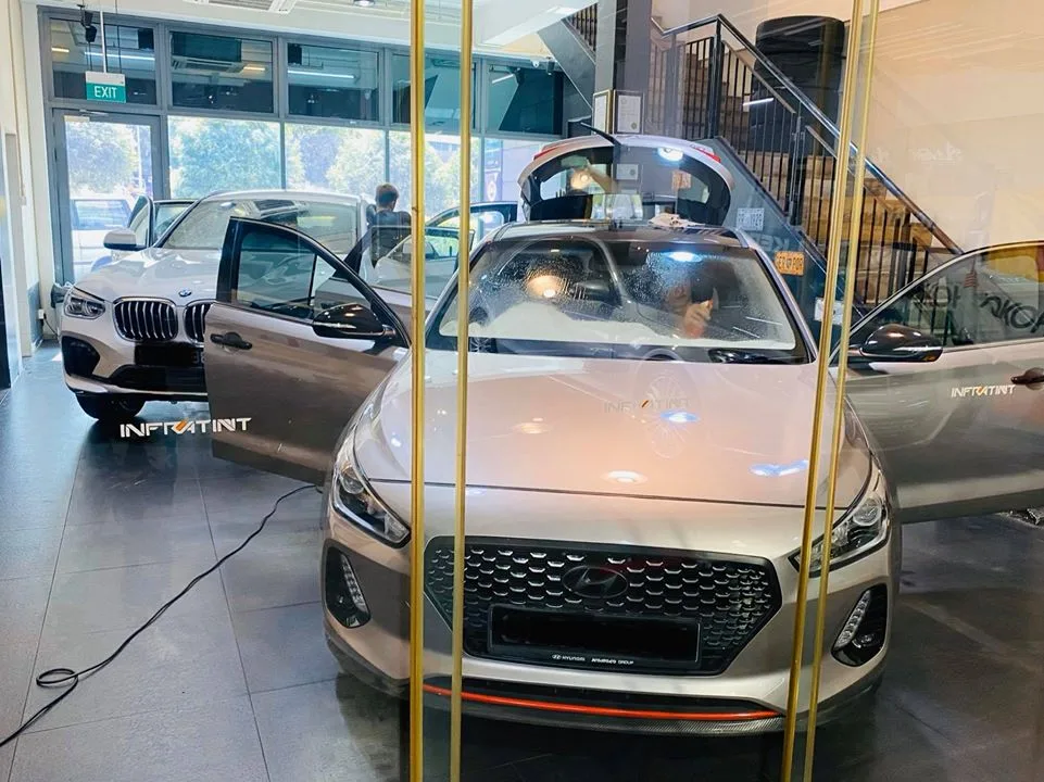 Silver Hyundai and white BMW SUV viewed through Infratint Singapore showroom glass