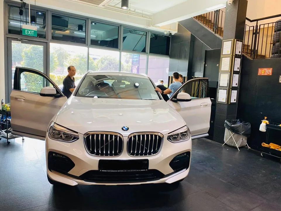 White BMW SUV with doors open being prepared for window tinting at Infratint Singapore