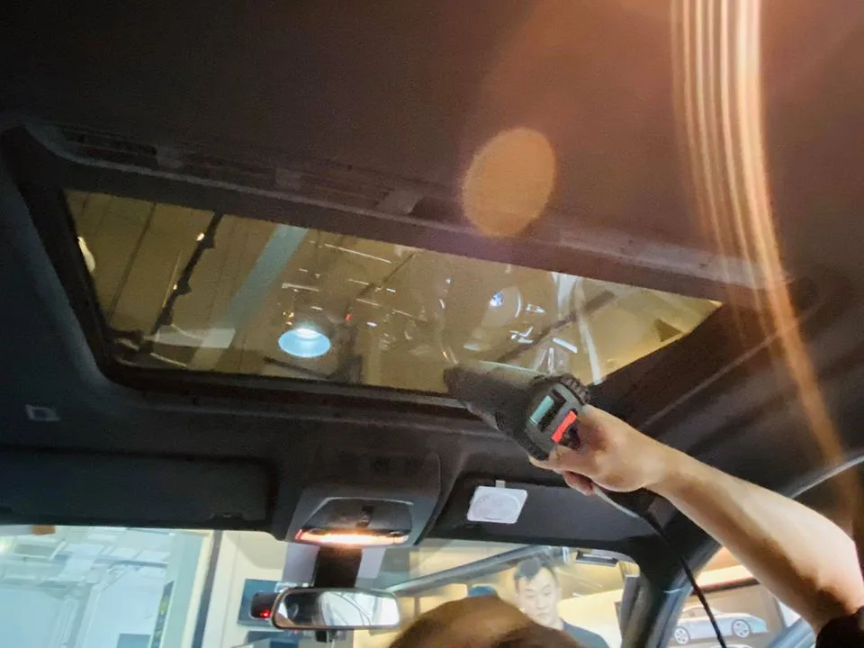 Technician applying film to the panoramic sunroof of a BMW X4 at Infratint Singapore