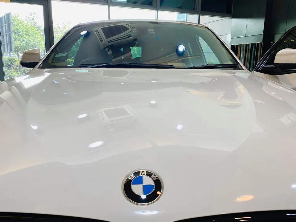 Close-up of a white BMW X4 bonnet badge and tinted windscreen at Infratint Singapore