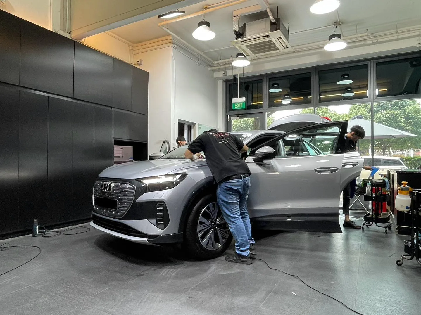 Installers fitting tint film to a silver Audi Q4 Sportback e-tron inside the Infratint workshop