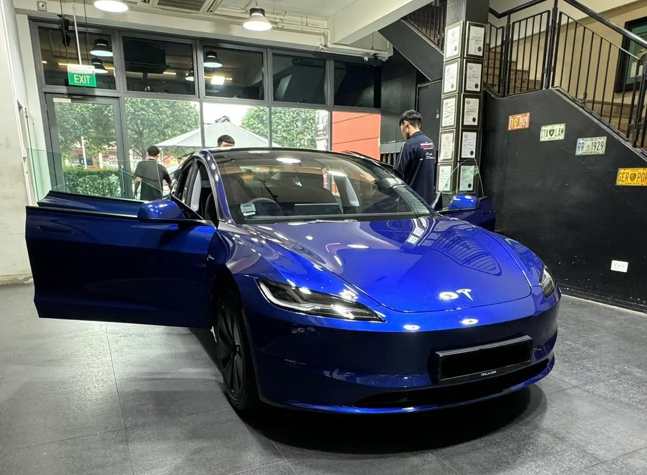 Blue Tesla M3H front three-quarter with door open inside Infratint Singapore workshop