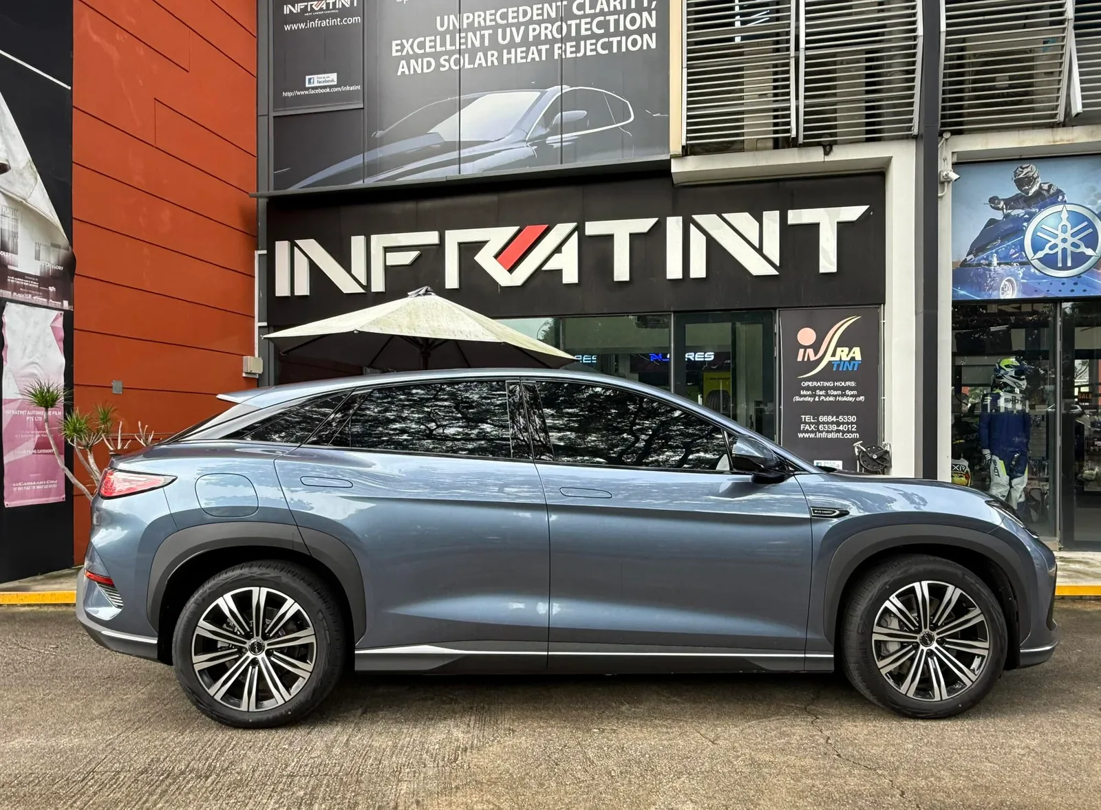 Tinted blue-grey BYD Sealion 7 side profile outside the Infratint shopfront in Singapore