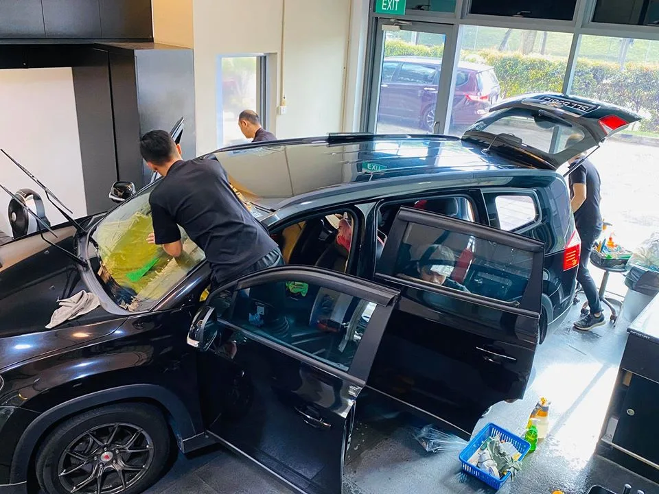 Technician applying window film to a black Chevrolet Orlando at Infratint Singapore
