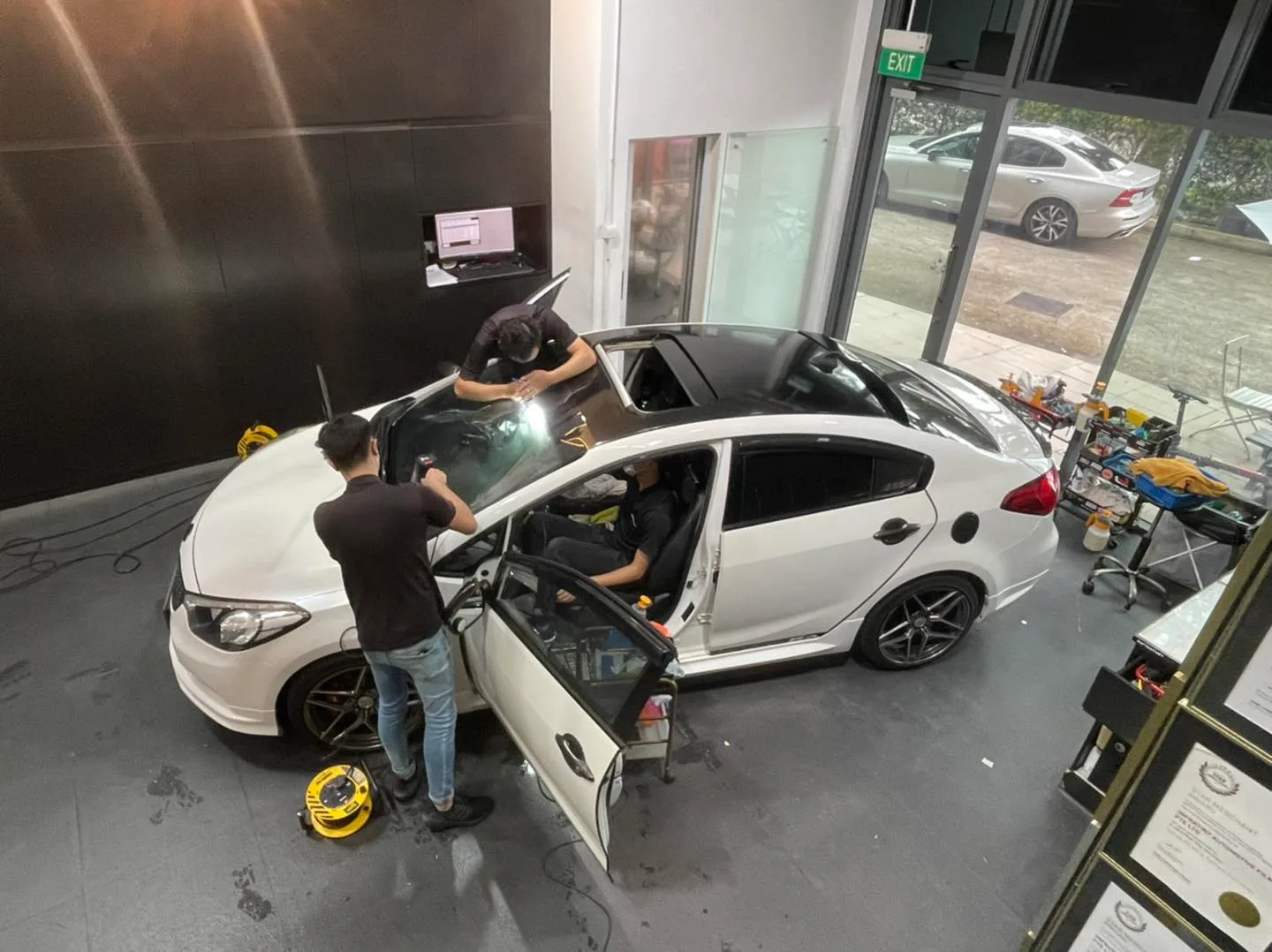 Overhead view of a white Kia sedan being tinted at Infratint Singapore