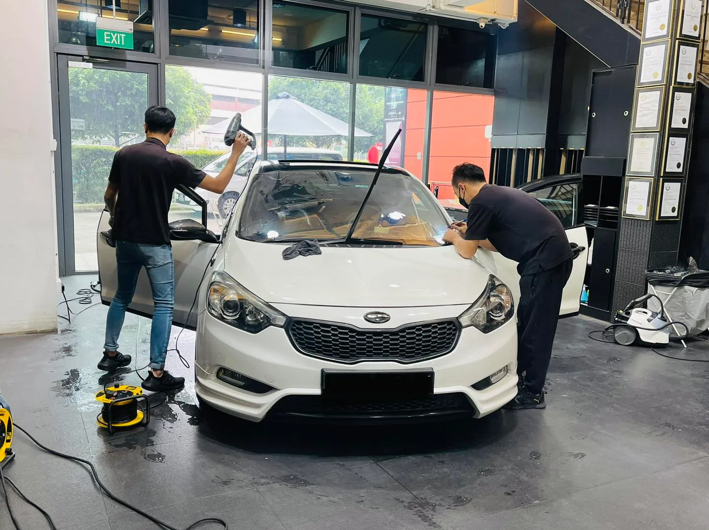 White Kia Cerato sedan with installers fitting window film at Infratint Singapore