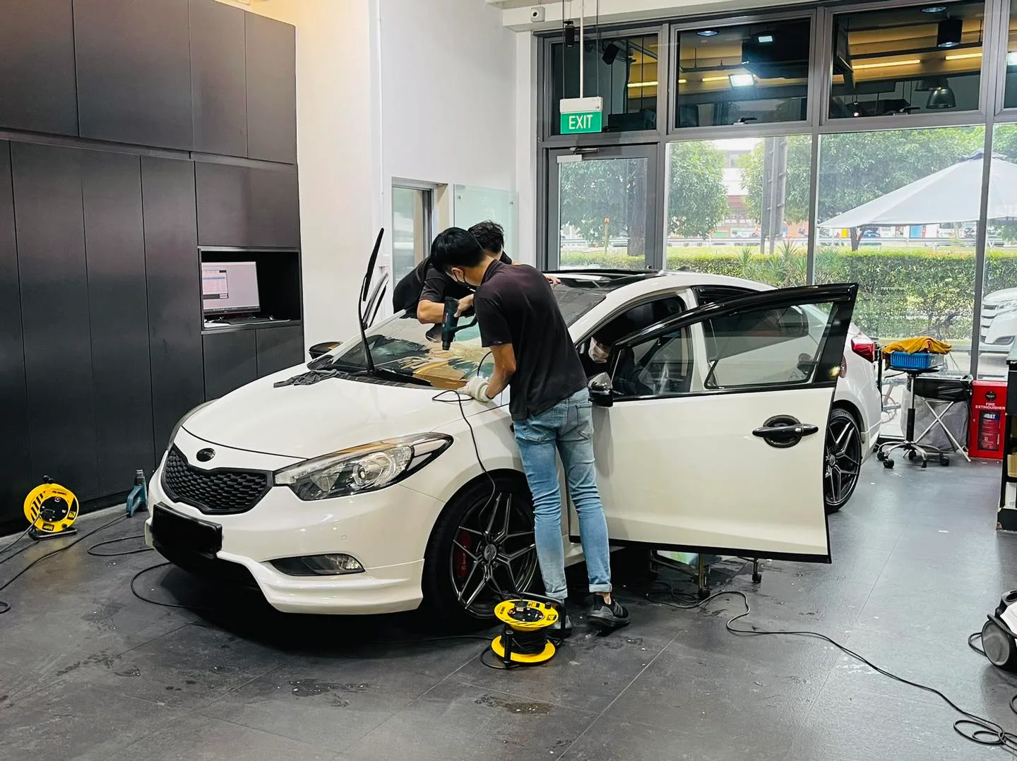 Side view of a white Kia sedan during window film install at Infratint Singapore