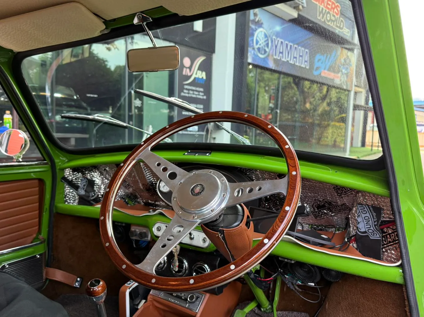 Classic MINI Cooper wood-rim steering wheel interior seen through tinted glass at Infratint Singapore