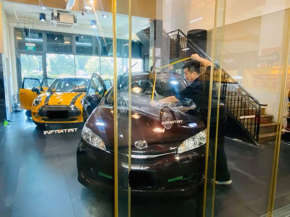 Installer applying window film to a brown MPV inside Infratint Singapore