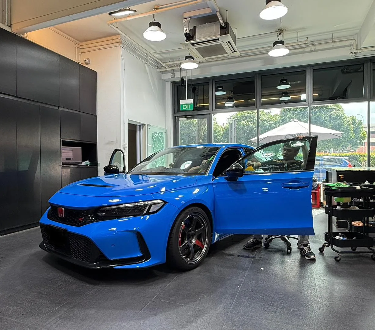 Installer fitting tint film to a blue Honda Civic Type R inside the Infratint workshop