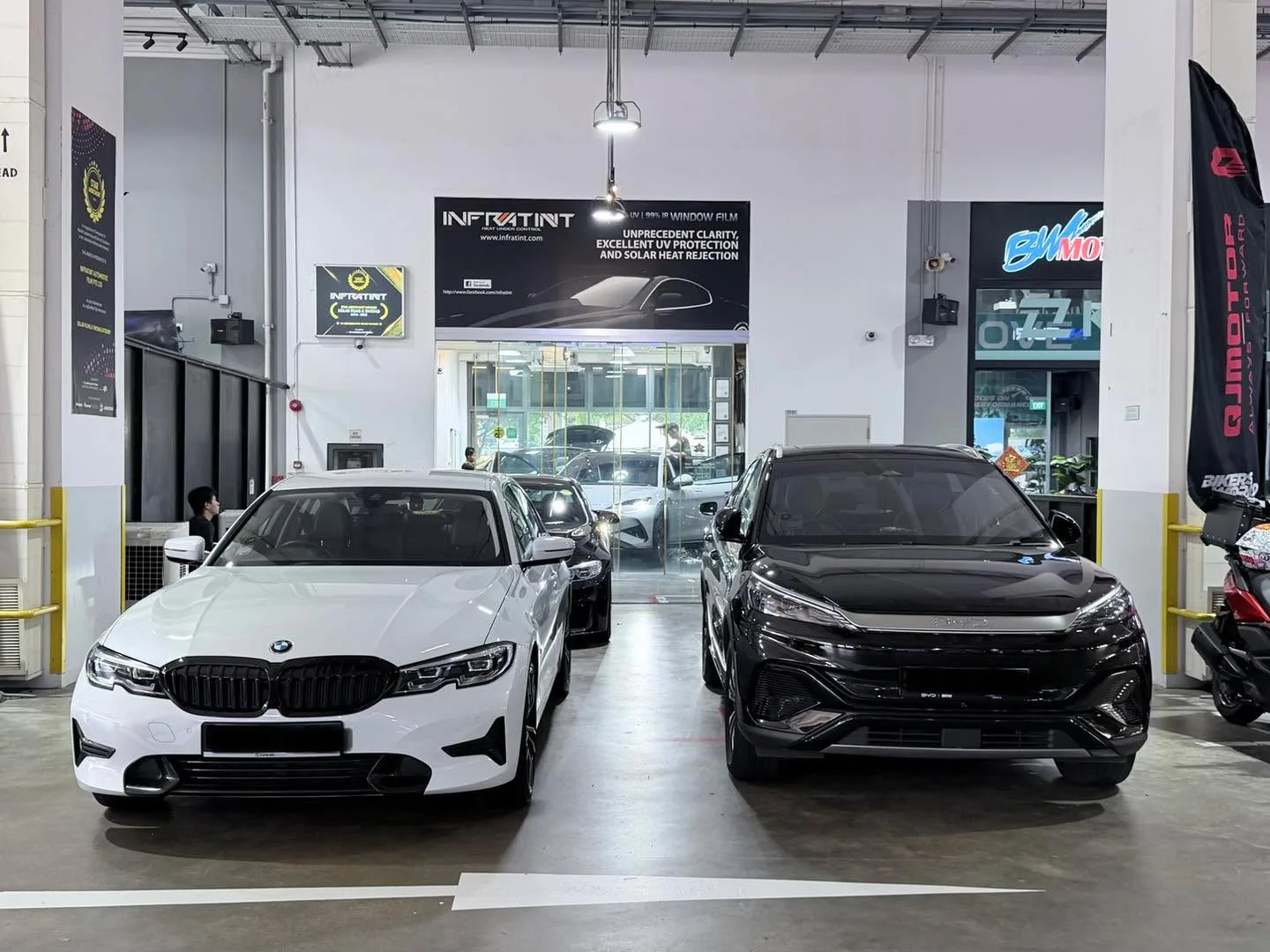 White BMW 3 Series and black SUV parked in the workshop.