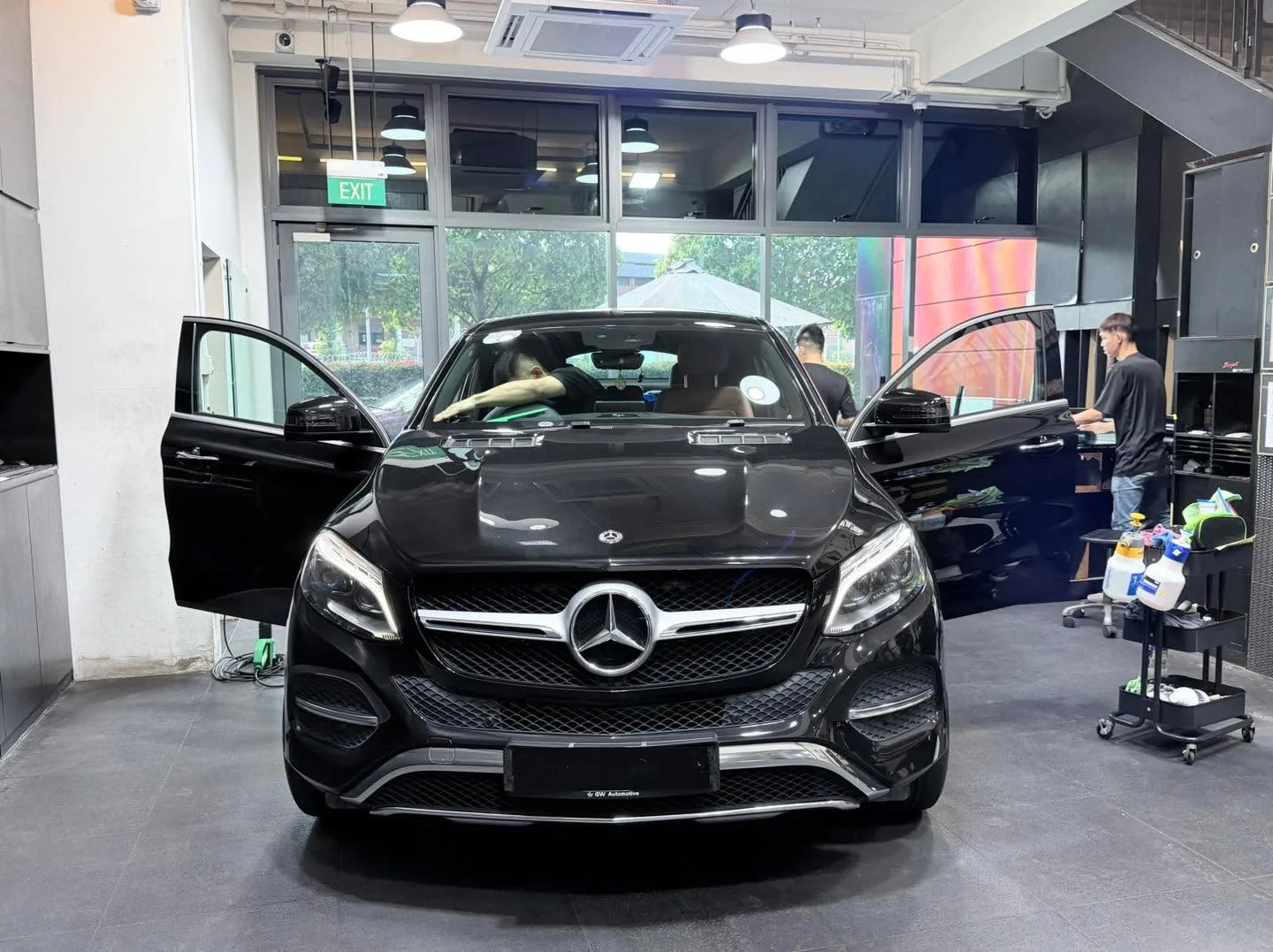 Black Mercedes-Benz GLE SUV with open driver door indoors.