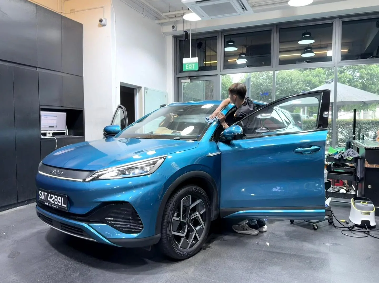 Blue BYD Atto 3 with open door during tinting work indoors.