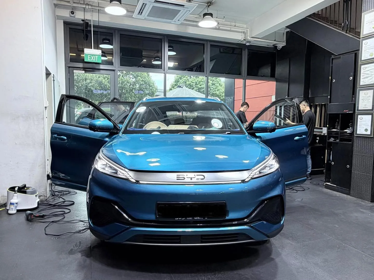 Blue BYD Atto 3 with doors open in the workshop.