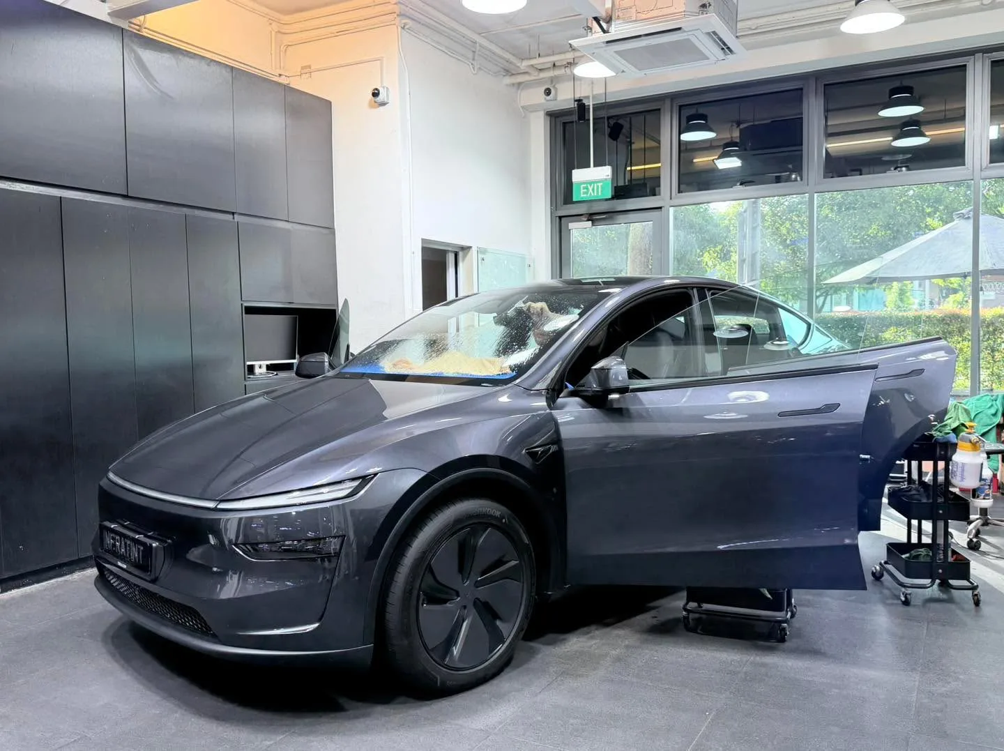 A dark-coloured sedan with both doors open in the workshop bay.