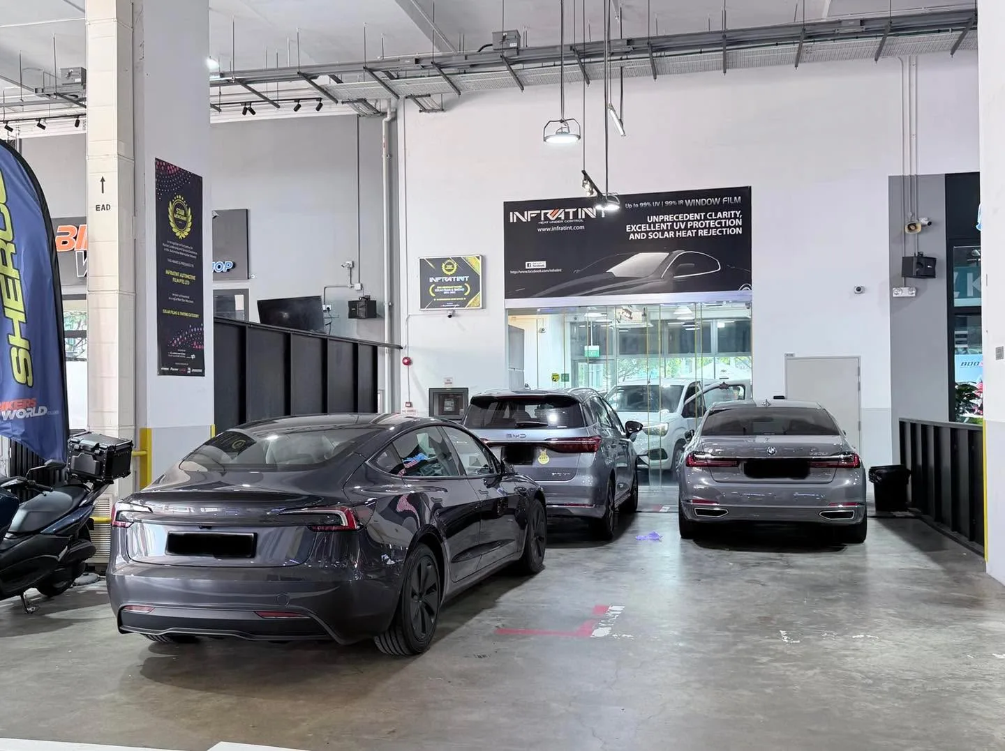 Dark grey Tesla sedans viewed from behind, parked in a line at the workshop.