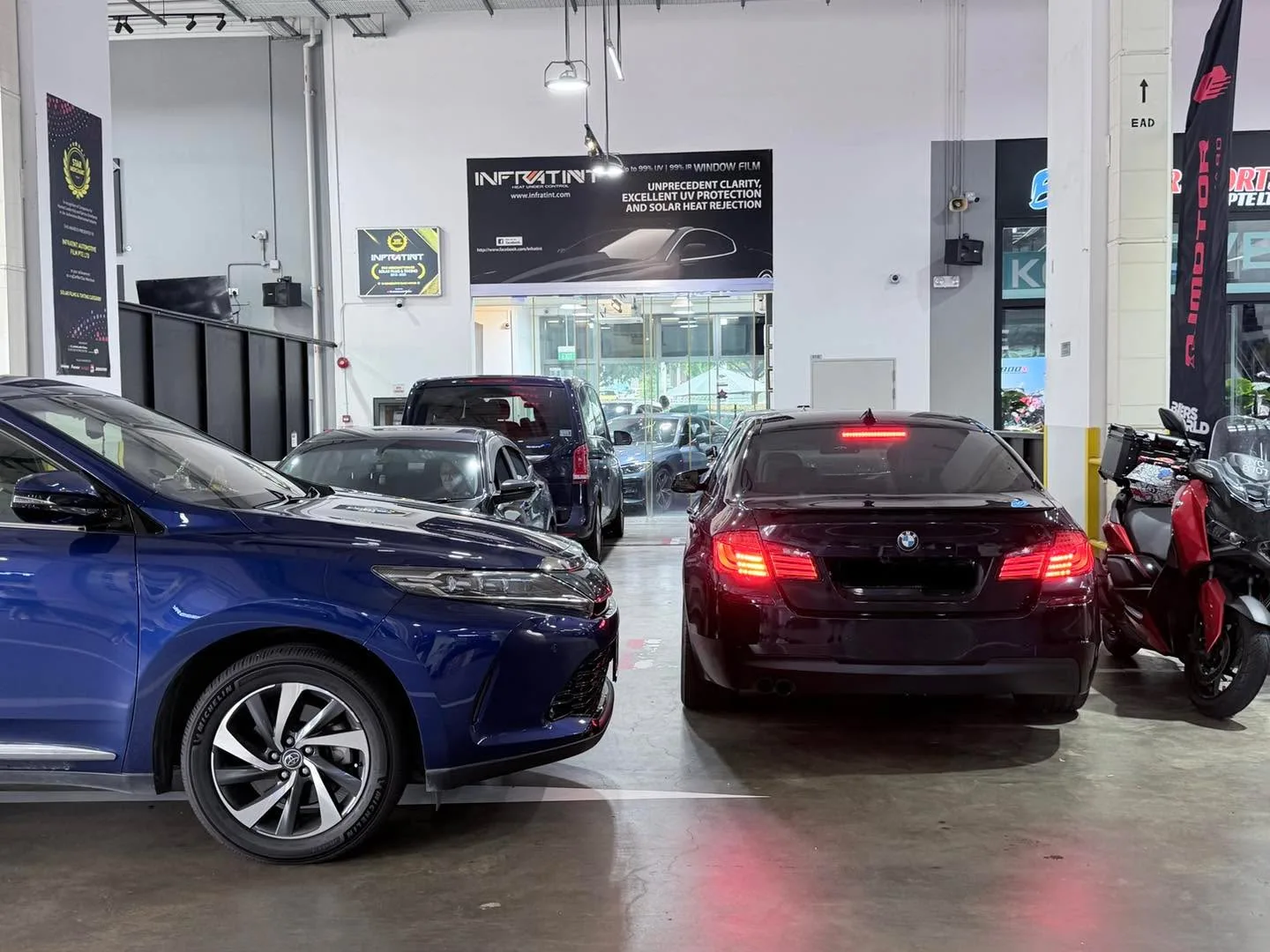 A blue saloon and a burgundy saloon parked in a workshop bay.