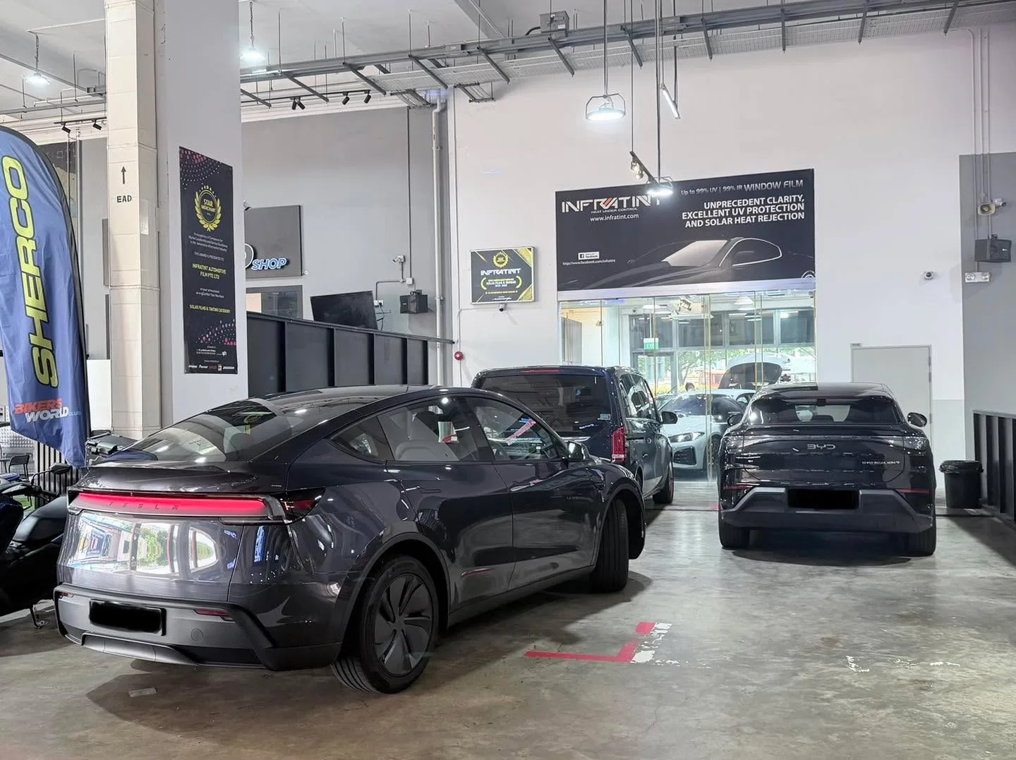 A black electric saloon and a black coupe in a workshop bay.