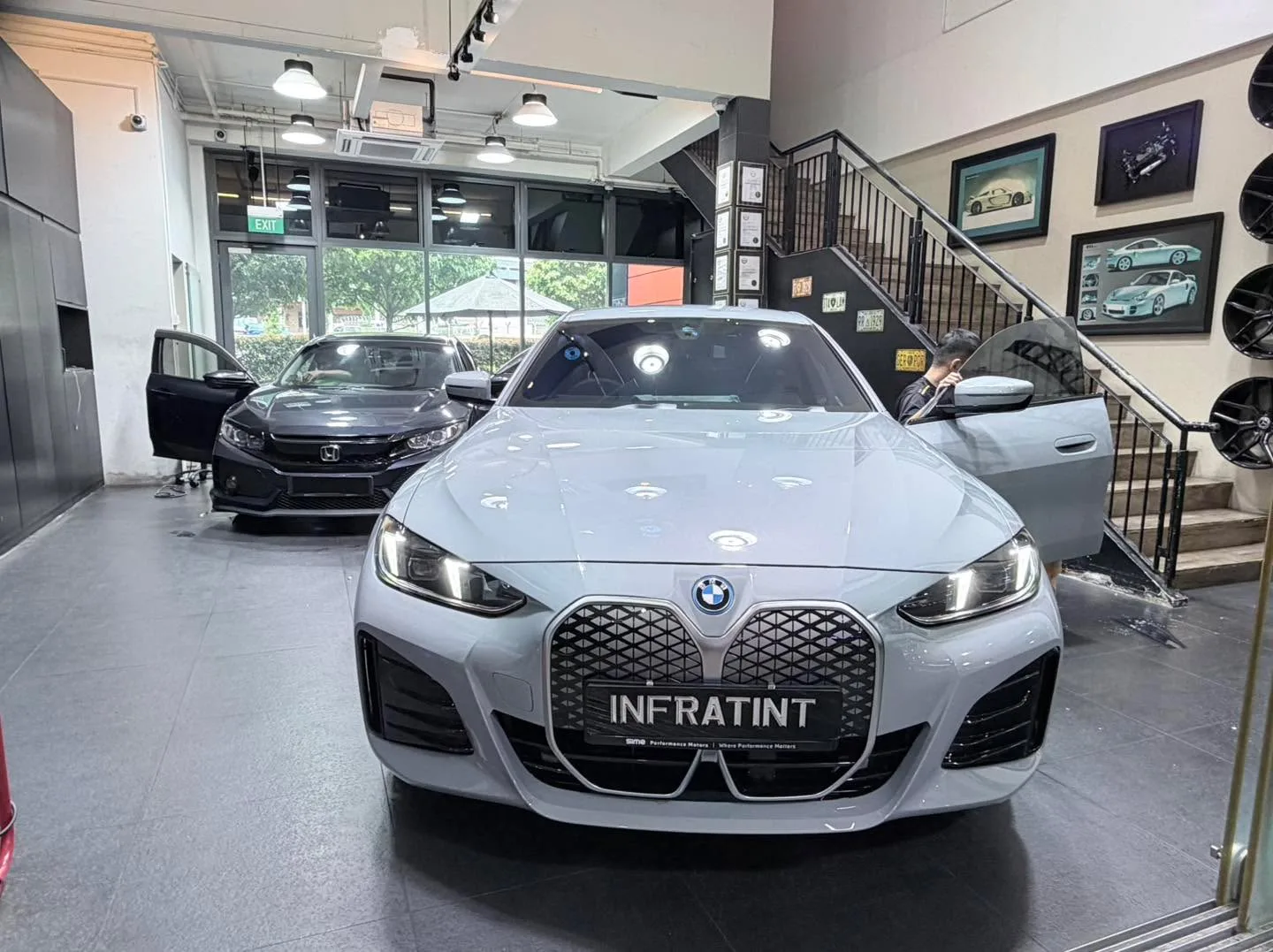 A white BMW saloon and a black Honda saloon on the workshop floor.