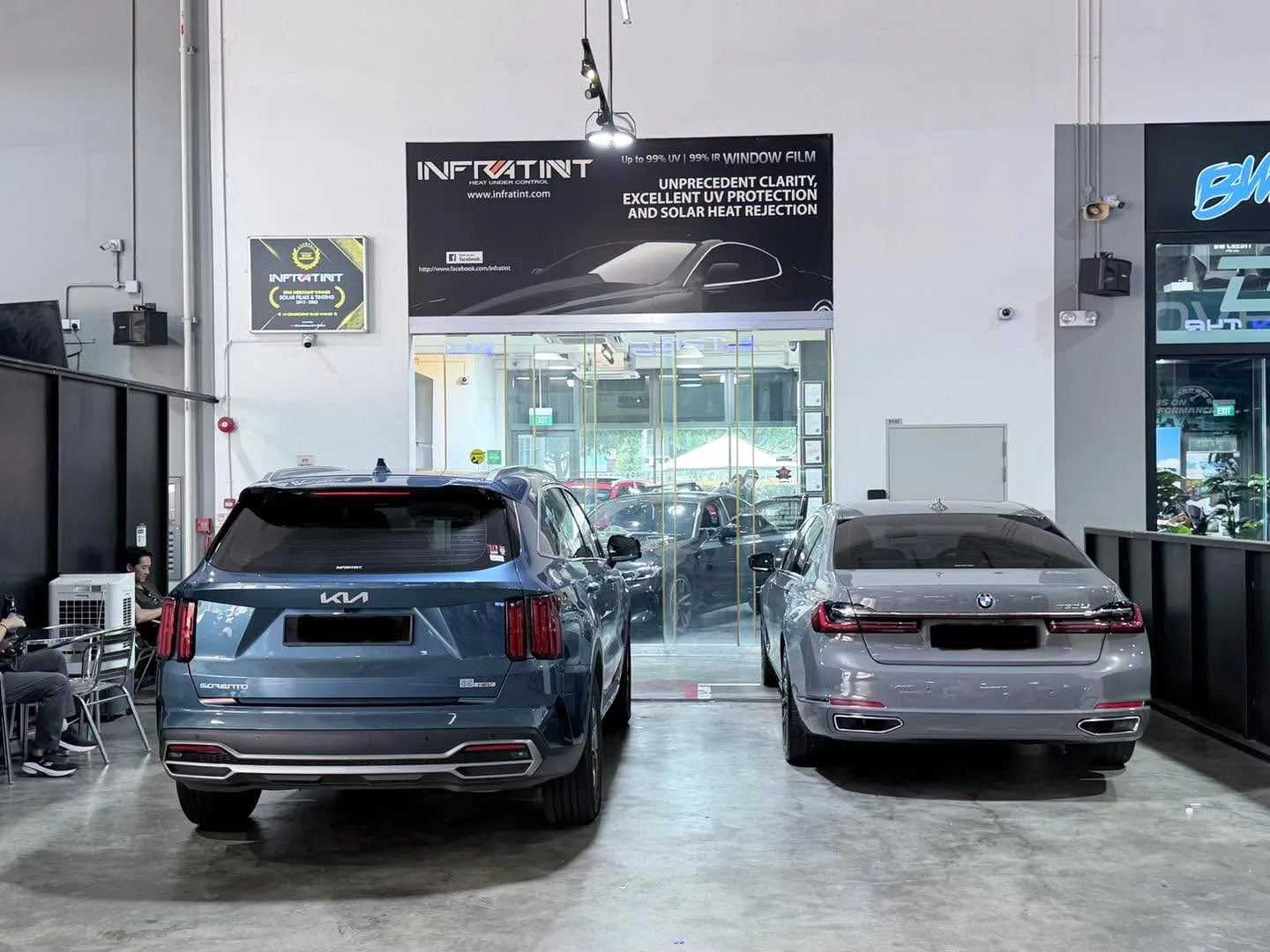 A blue Kia Sorento and grey Mercedes-Benz sedan parked outside the Infratint workshop.