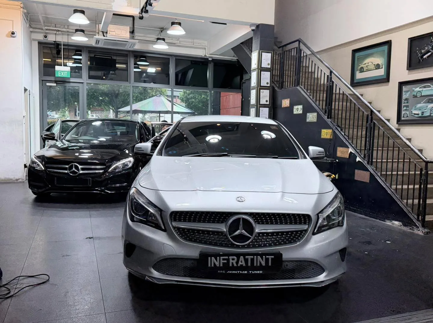 A white Mercedes-Benz C-Class and black Mercedes-Benz sedan parked inside the workshop.