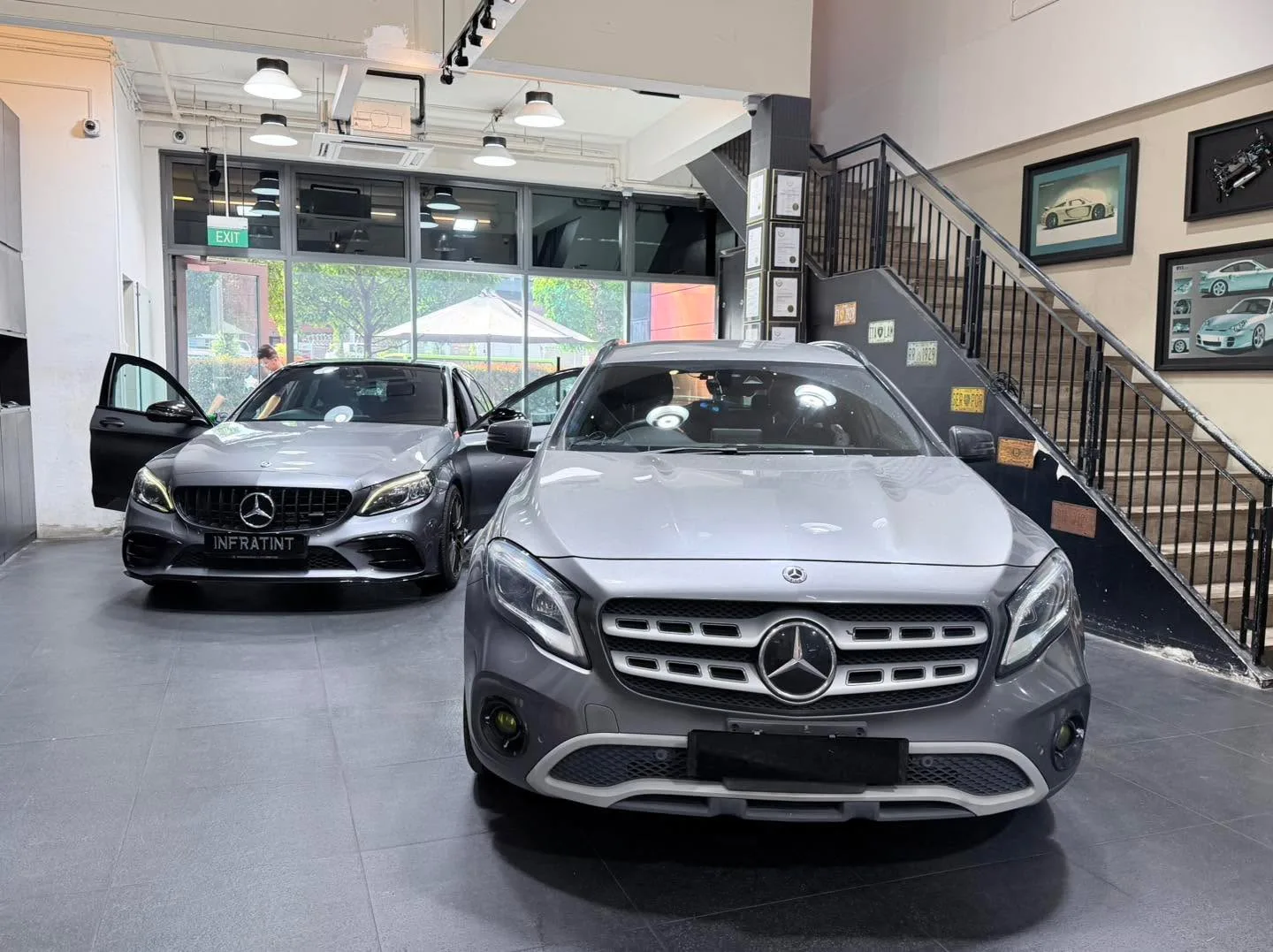 A grey Mercedes-Benz GLA compact SUV with open driver door inside the workshop.