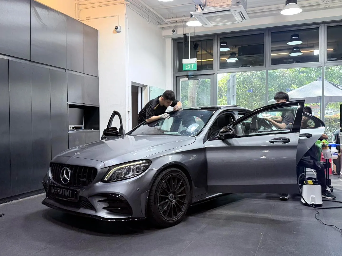 A white sedan with open driver and passenger doors in the workshop.