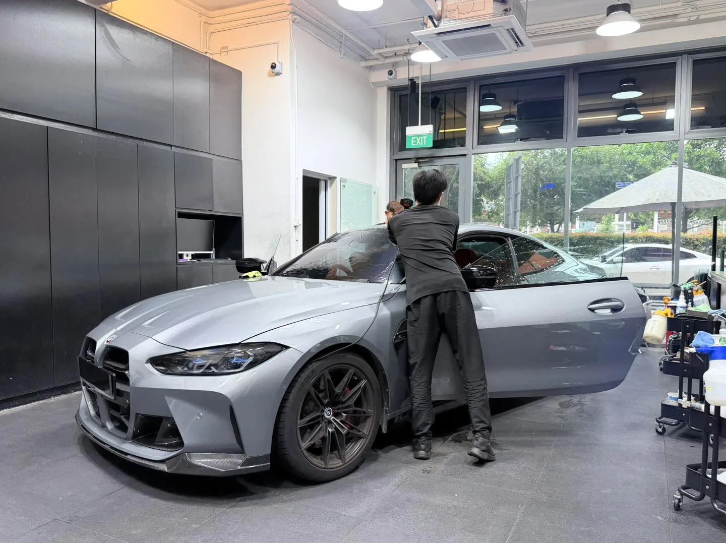A white Tesla sedan with doors open, seen from the side, technicians working on the windows.