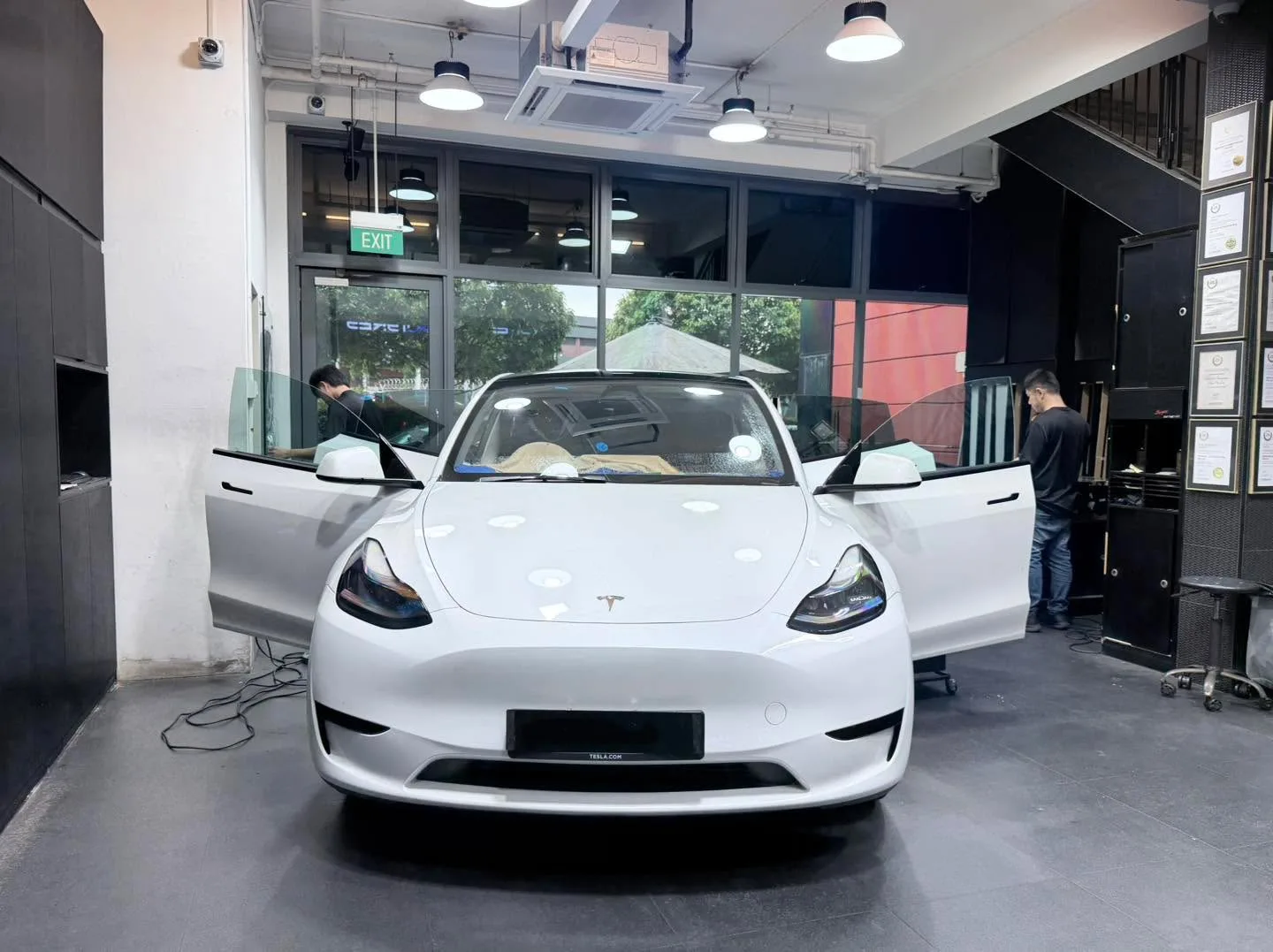 A white Hyundai Avante sedan with all four doors open, viewed from behind, technicians working on windows.