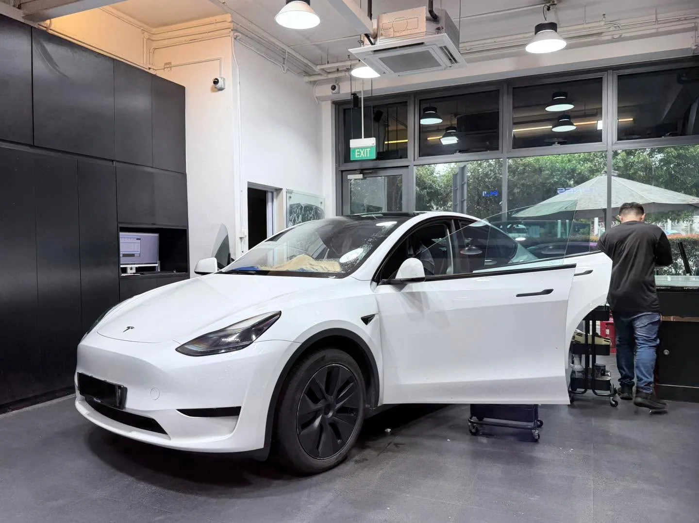 A white Hyundai Avante compact sedan with doors open, technicians visible working on the side windows.