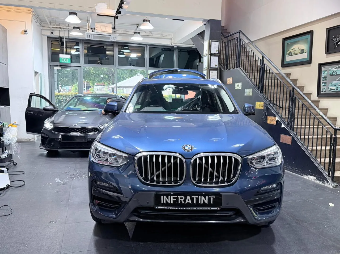 A blue BMW X3 with open doors in the workshop interior.