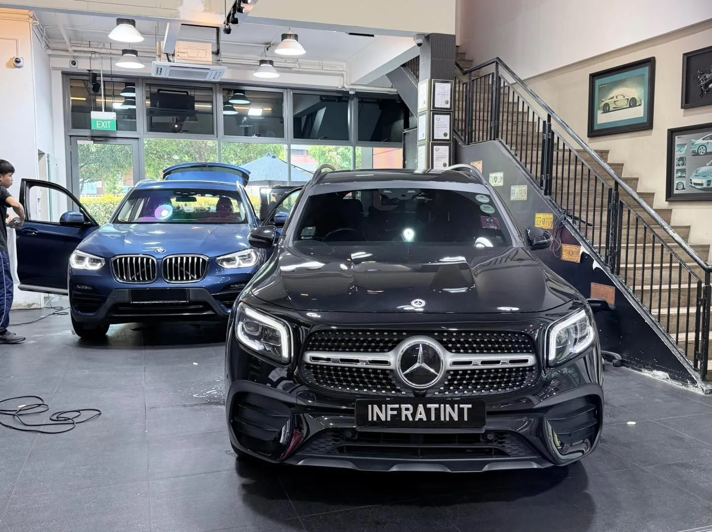 A black Mercedes-Benz GLB and a blue BMW X3 inside the facility.