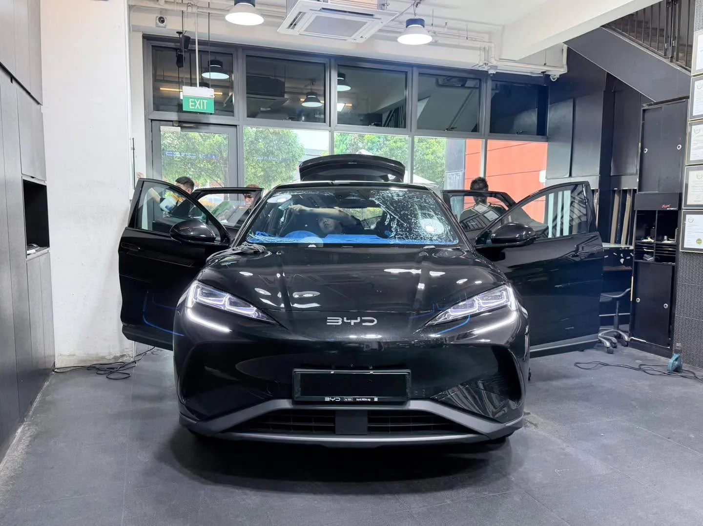 A black BYD Sealion 7 with doors fully open in the workshop.