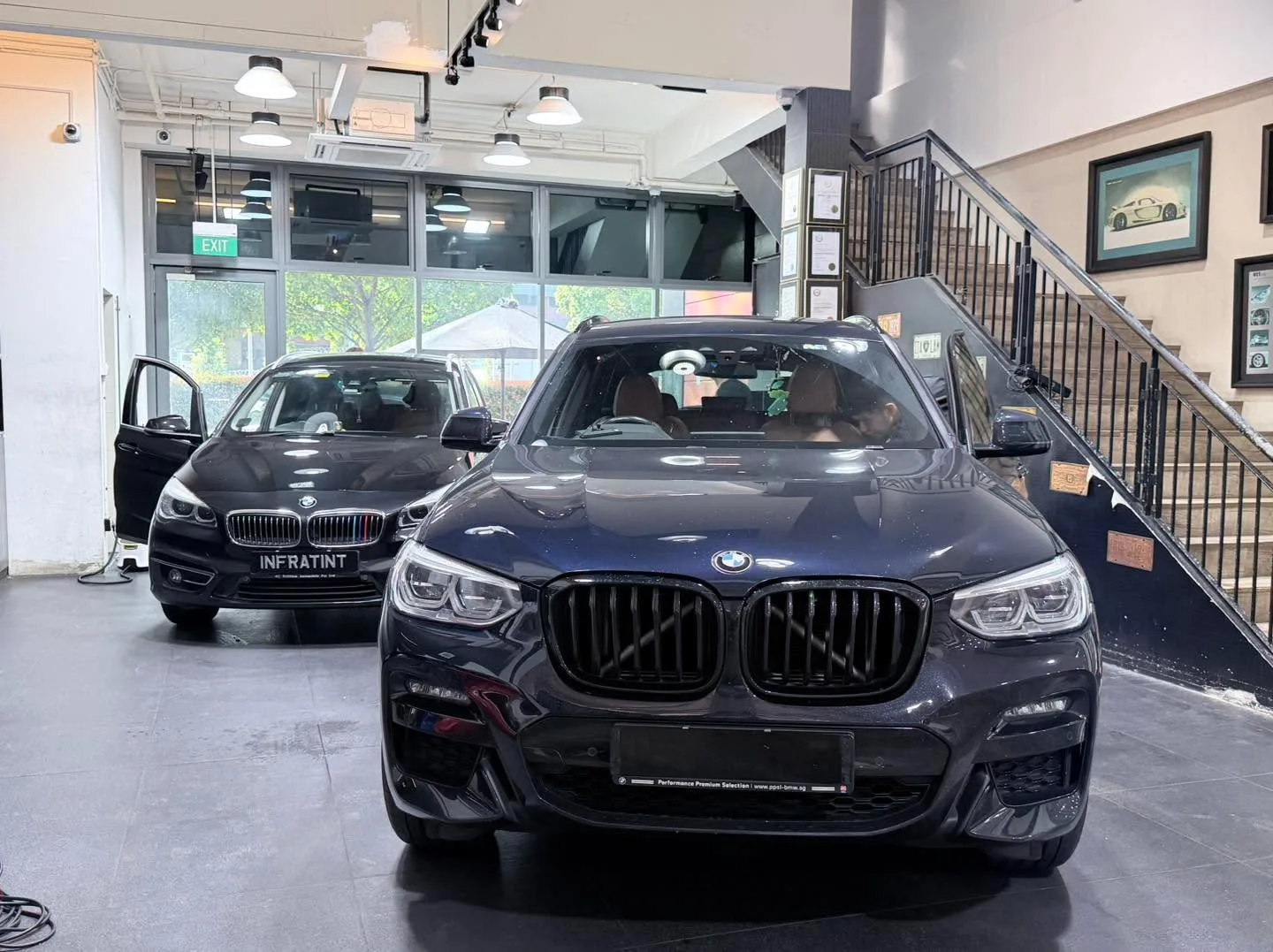 A dark-coloured BMW X3 and another car inside the workshop space.