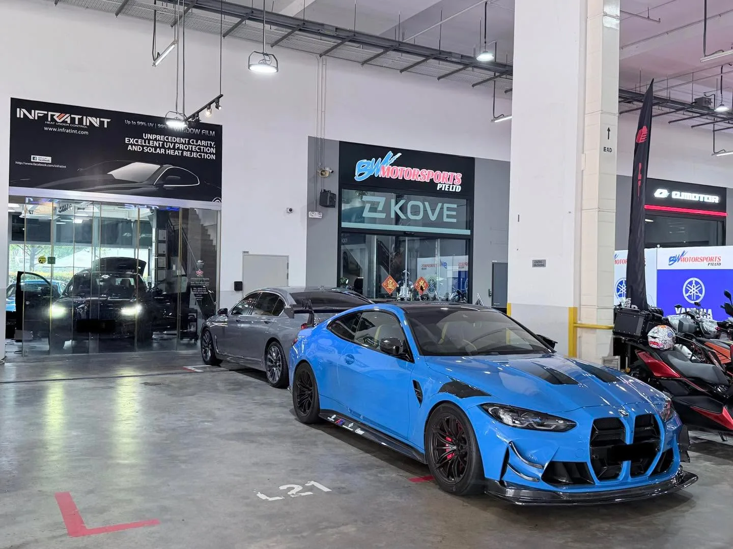 A bright blue BMW M2 coupe parked in a workshop bay at Infratint.