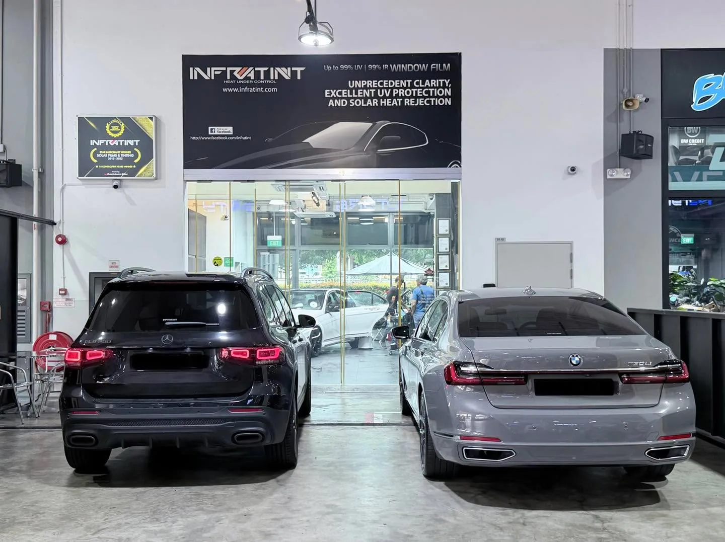 A black Mercedes-Benz GLB and a grey BMW saloon parked side by side indoors.