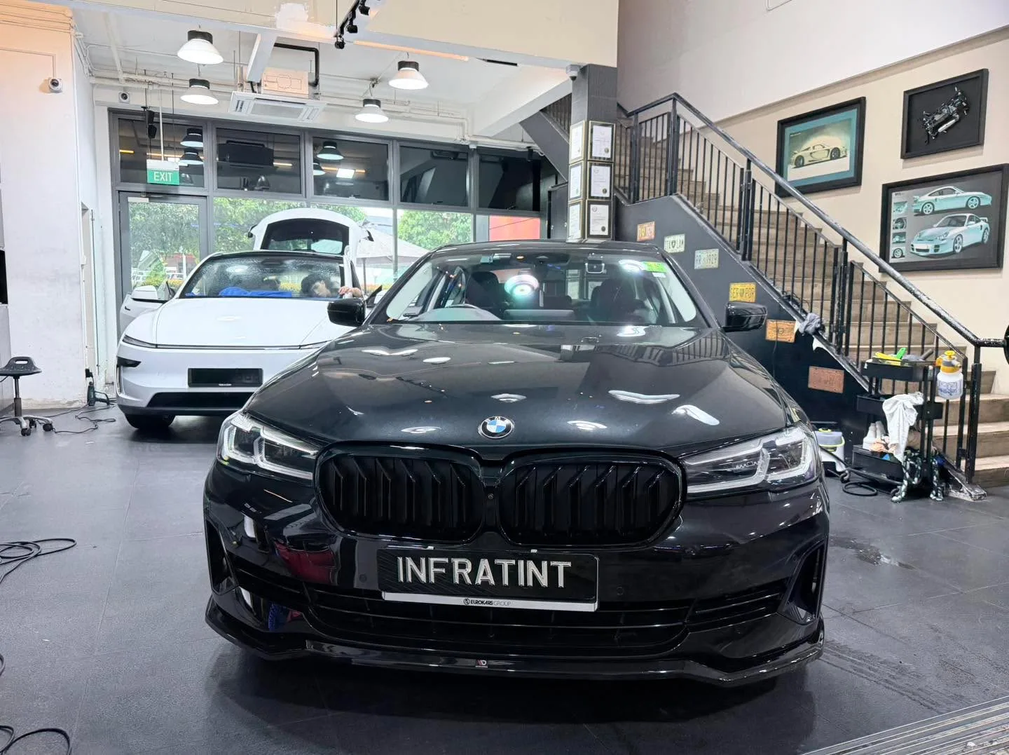A black BMW 520 saloon parked indoors, facing away from the camera.
